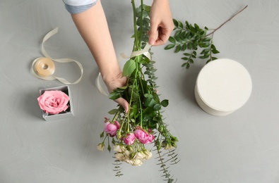 Photo of Female florist making beautiful bouquet at table, top view