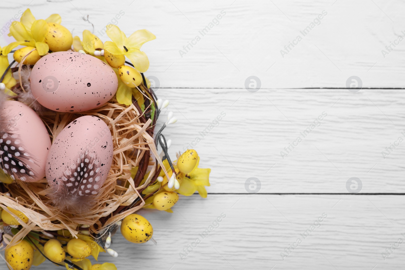 Photo of Festively decorated Easter eggs on white wooden table, top view. Space for text