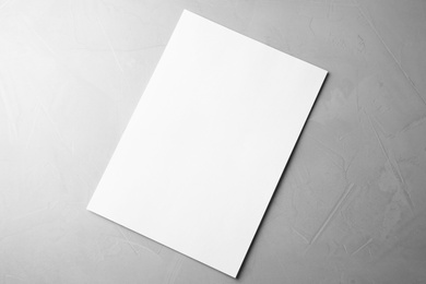 Photo of Blank paper sheet on light grey stone background, top view. Mock up for design