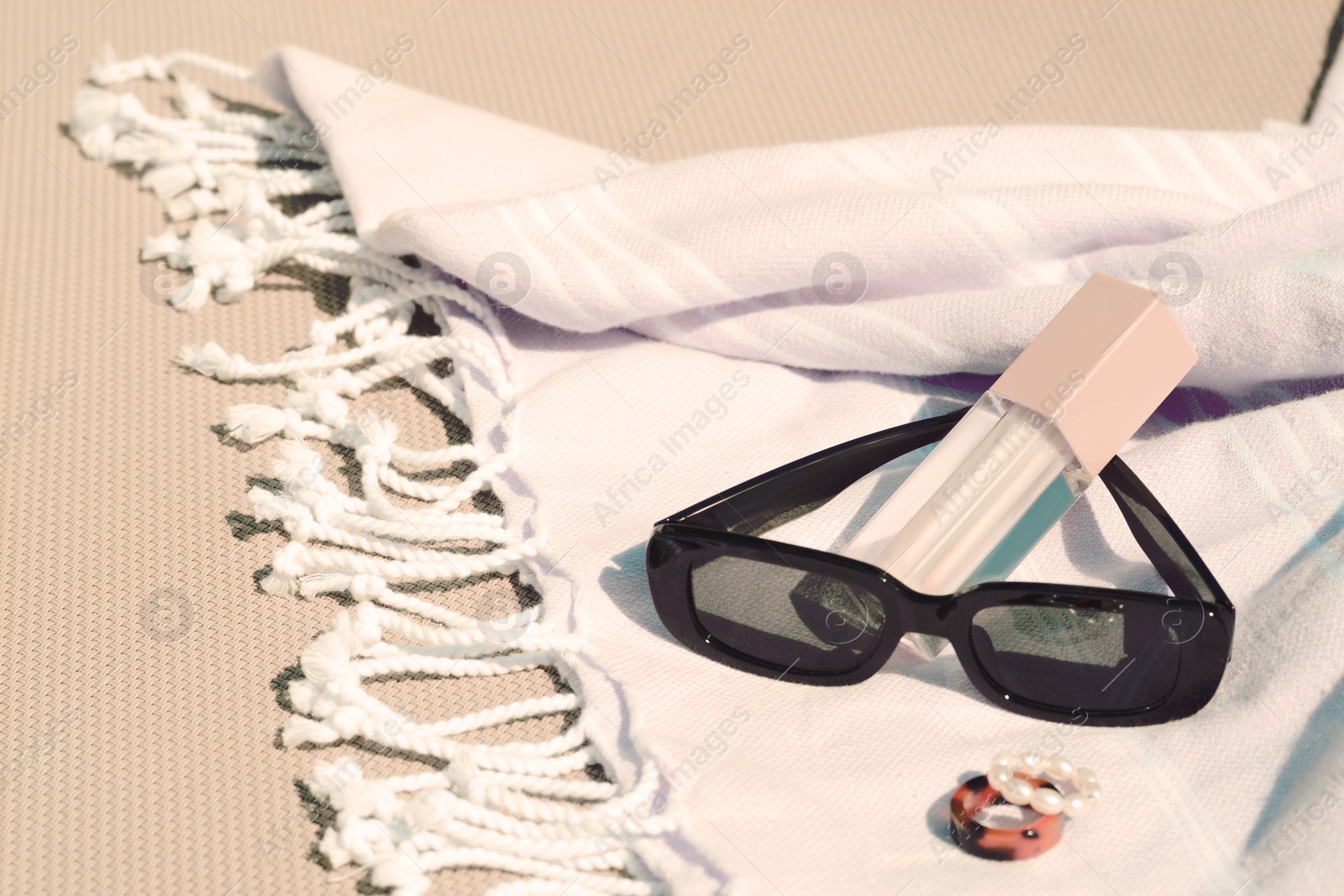 Photo of Stylish sunglasses, jewelry and lip gloss on grey surface, space for text