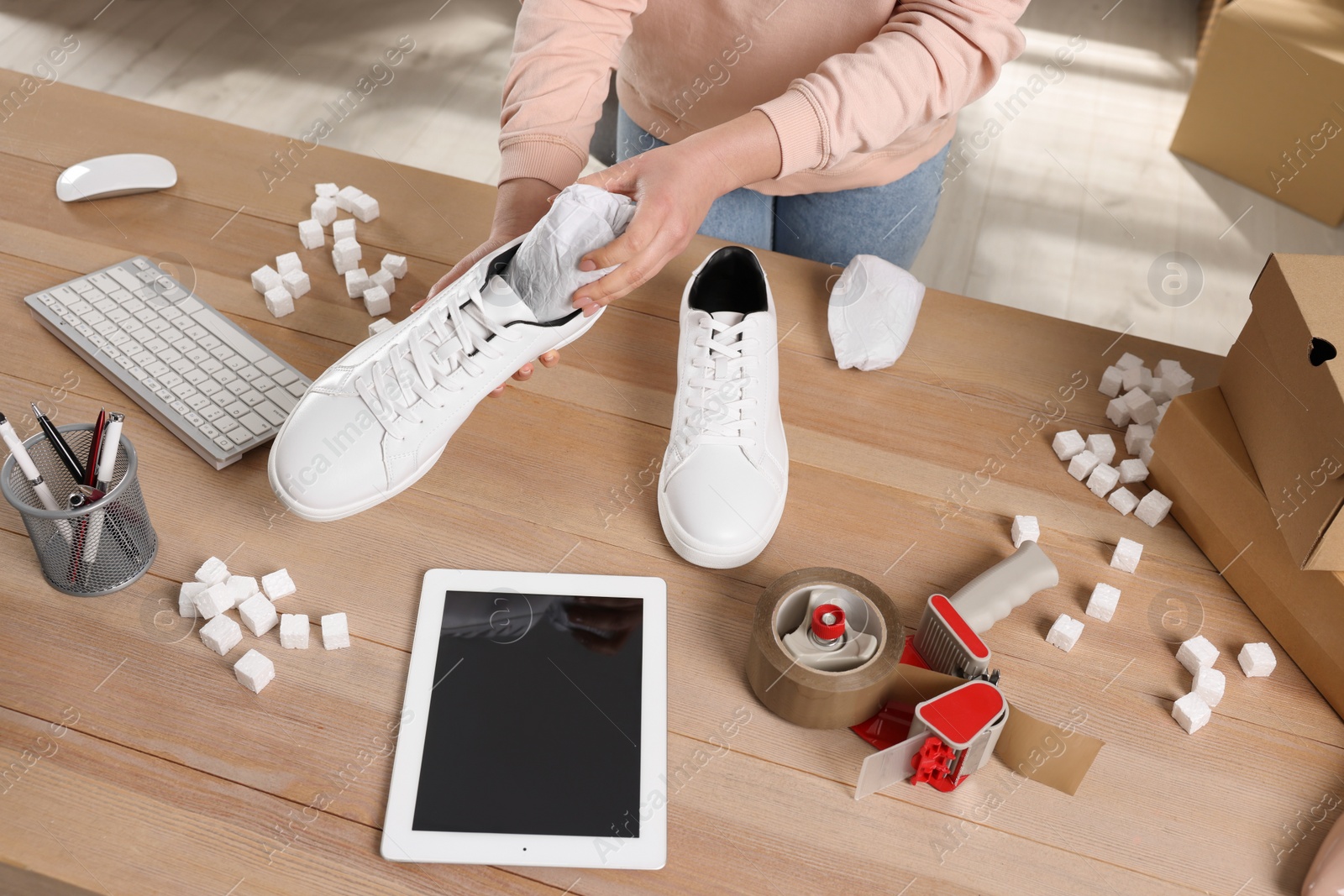 Photo of Seller packing shoes at workplace, above view. Online store