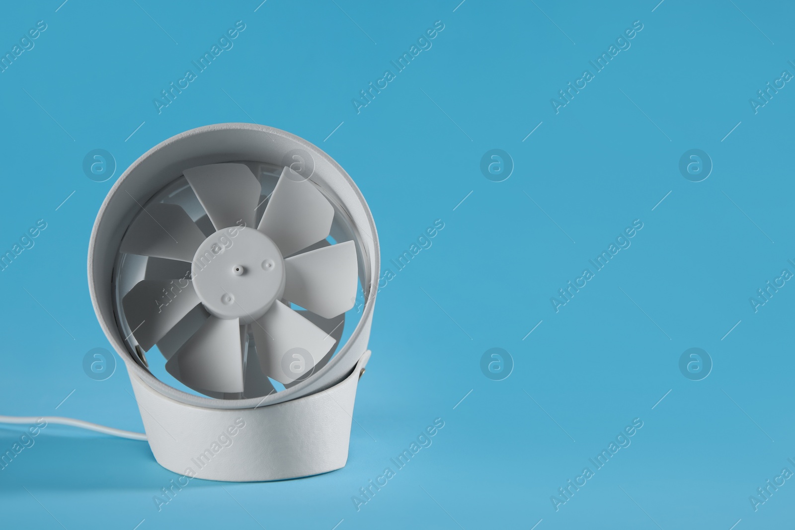 Photo of Modern electric fan on light blue background. Space for text