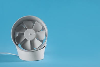 Modern electric fan on light blue background. Space for text