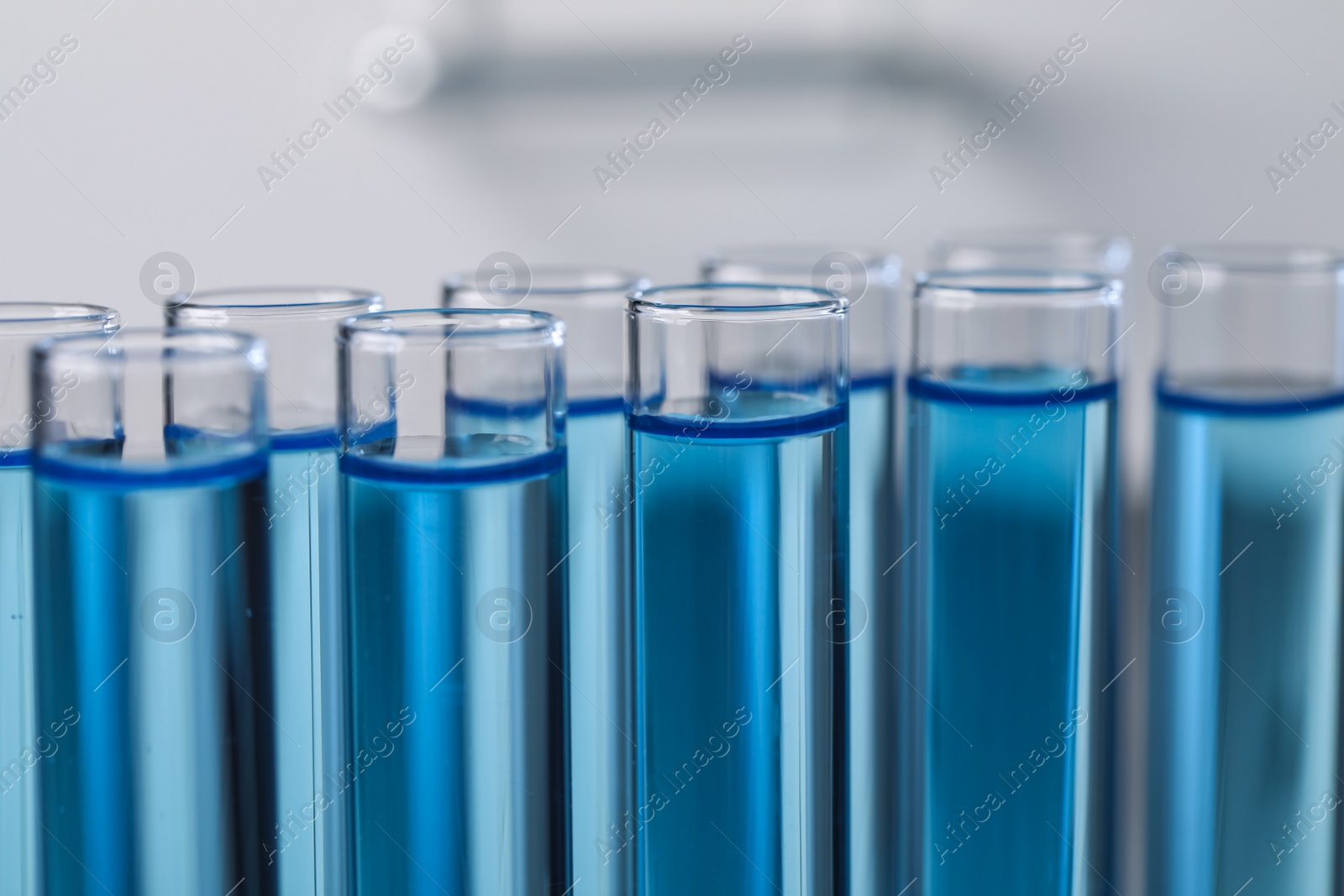 Photo of Test tubes with reagents on blurred background, closeup. Laboratory analysis