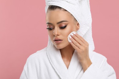 Photo of Beautiful woman removing makeup with cotton pad on pink background