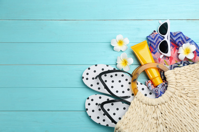 Photo of Bag with beach accessories on light blue wooden background, flat lay. Space for text