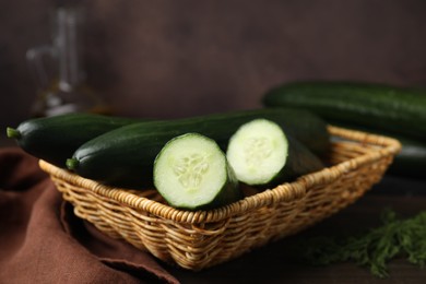 Photo of Fresh cucumbers in wicker basket on table, closeup