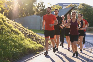 Group of people running outdoors on sunny day. Space for text