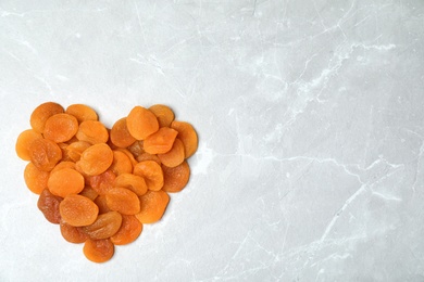 Heart made of apricots on grey background, top view with space for text. Dried fruit as healthy food