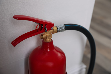 Photo of Fire extinguisher near white wall indoors, closeup