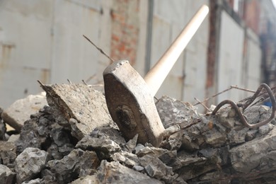 Sledgehammer on pile of broken stones outdoors, closeup