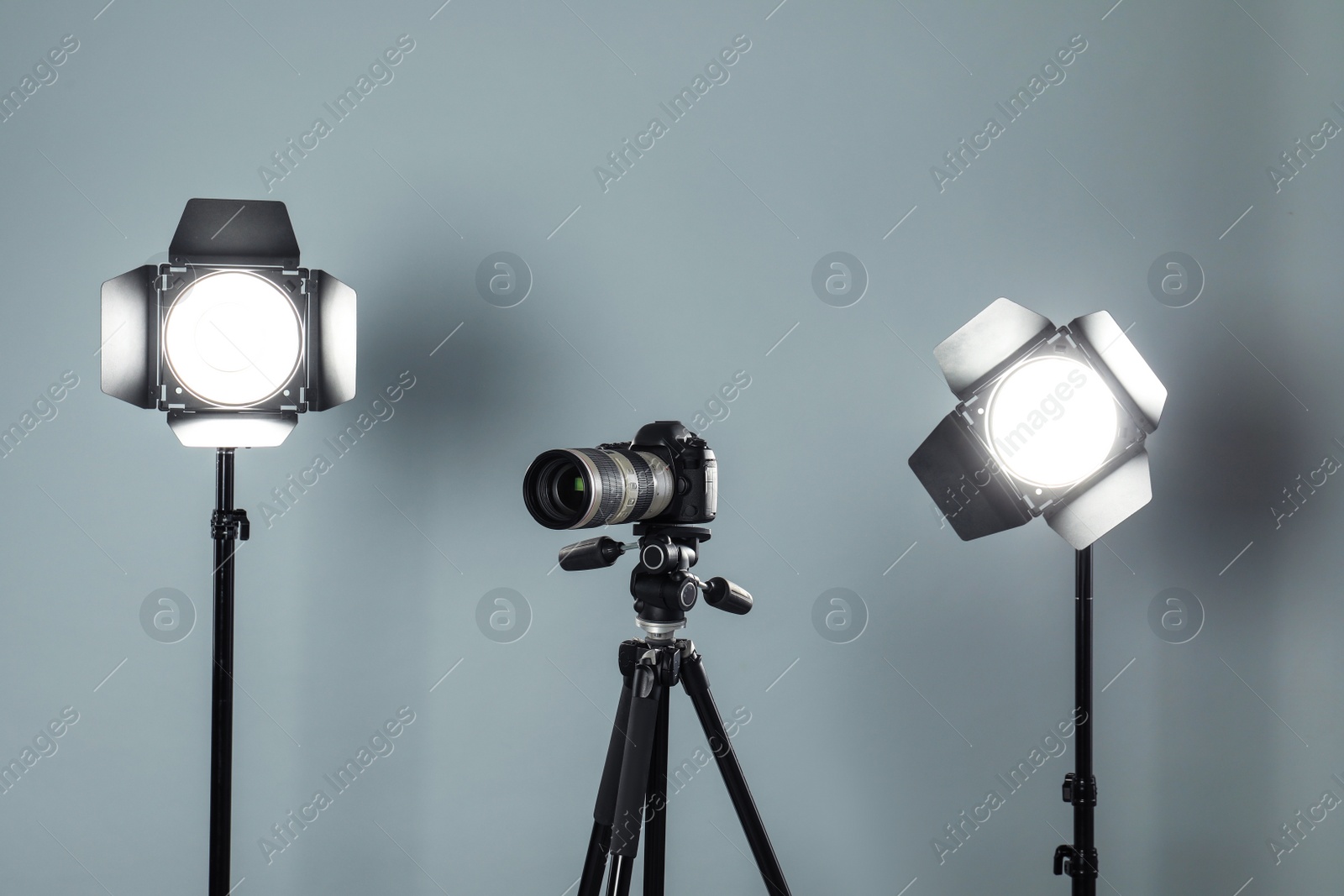 Photo of Professional video camera and lighting equipment on grey background