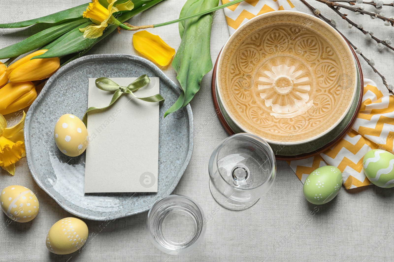 Photo of Festive Easter table setting with blank card on color background, top view. Space for text