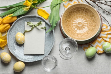 Festive Easter table setting with blank card on color background, top view. Space for text