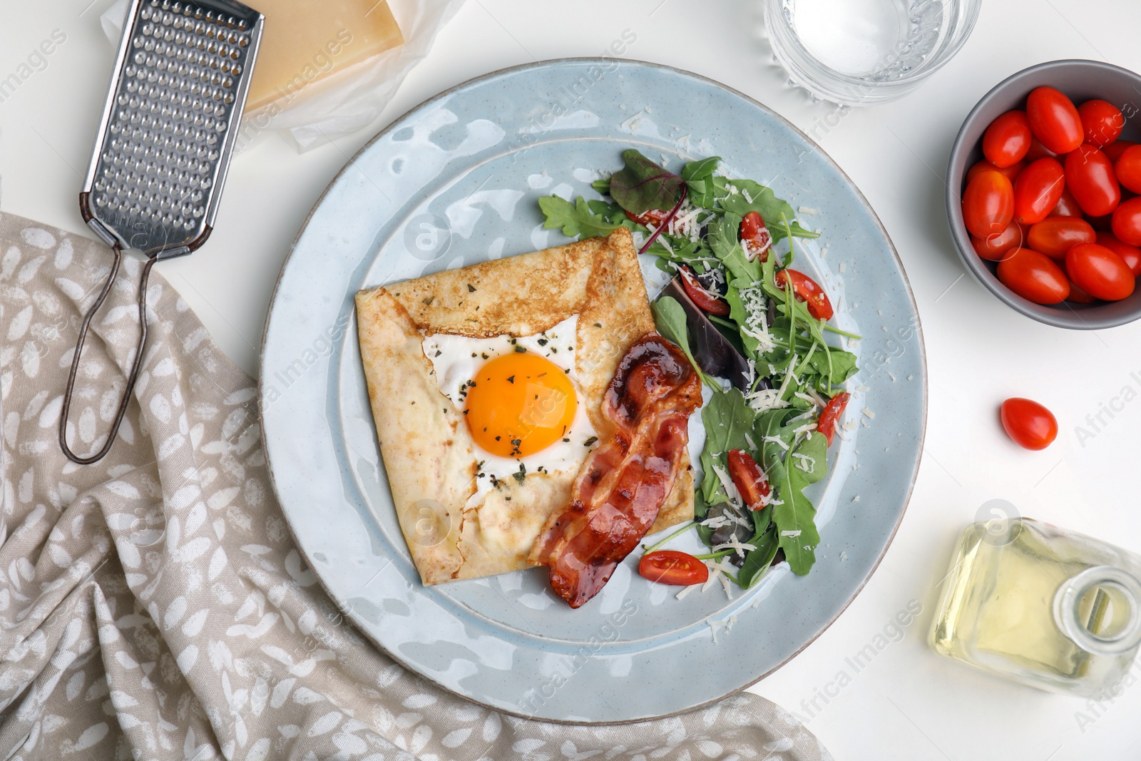 Photo of Delicious crepe with egg served on white table, flat lay. Breton galette