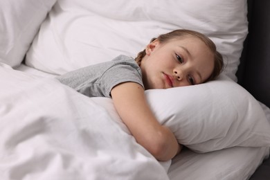 Photo of Little girl suffering from headache in bed