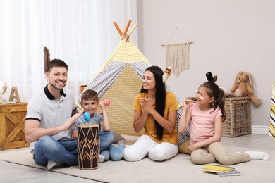 Photo of Happy family playing together near toy wigwam at home