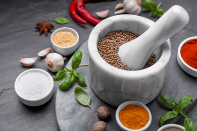 Photo of Mortar with pestle and different spices on black table