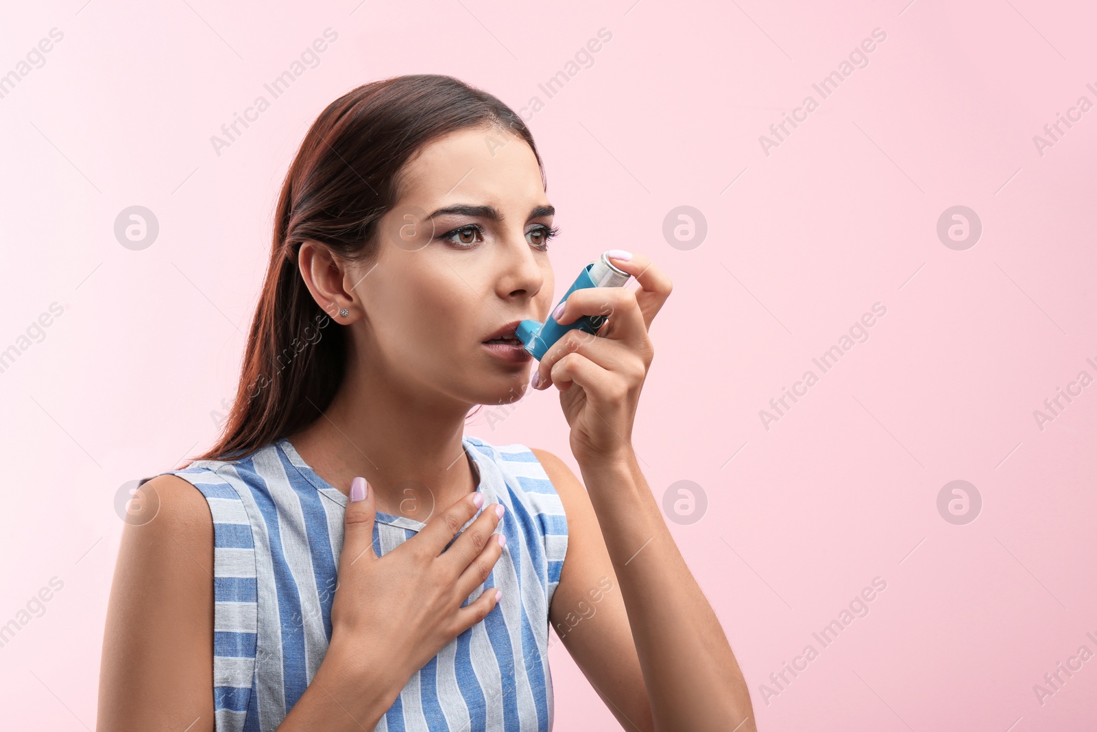 Photo of Young woman using asthma inhaler on color background. Space for text