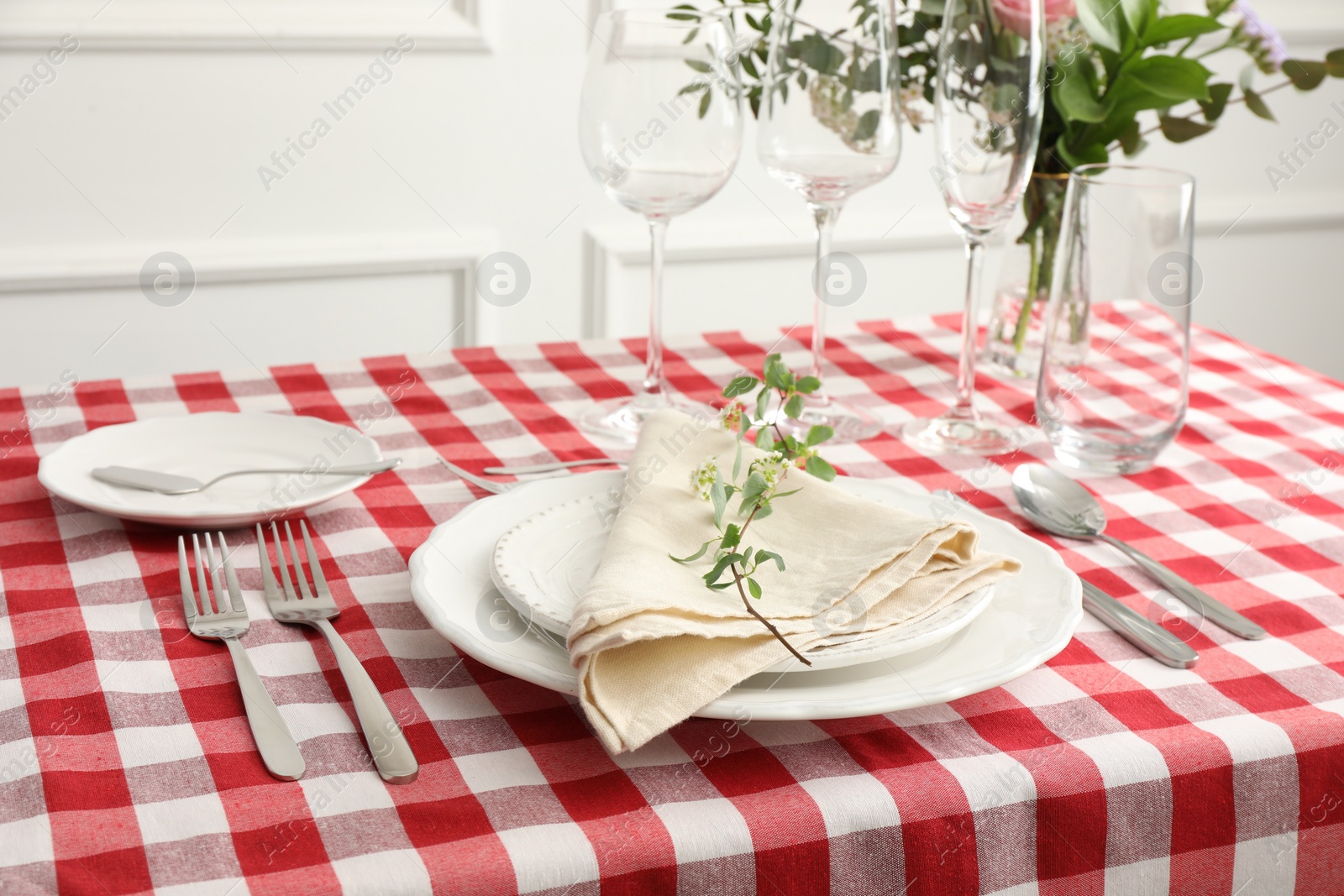 Photo of Stylish setting with cutlery, plates, napkin, glasses and floral decor on table