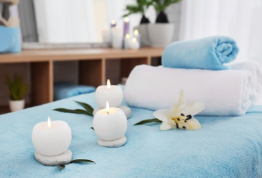 Photo of Towels, candles and stones on massage table in spa salon