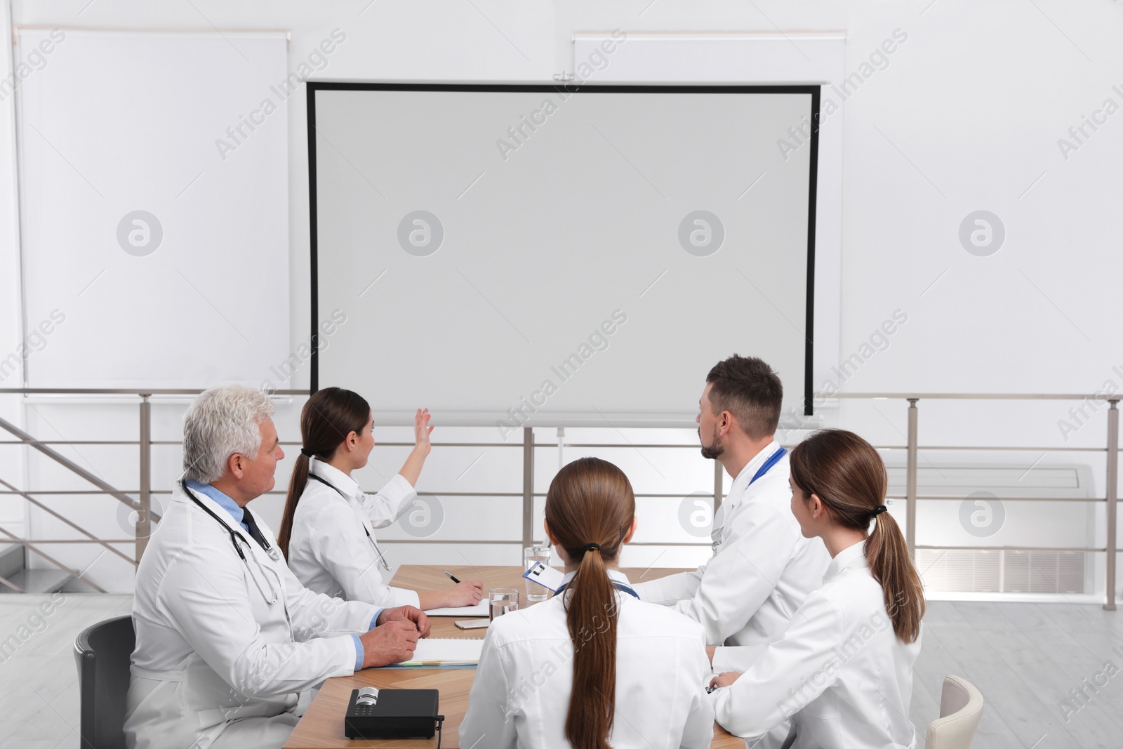 Photo of Team of doctors using video projector during conference indoors