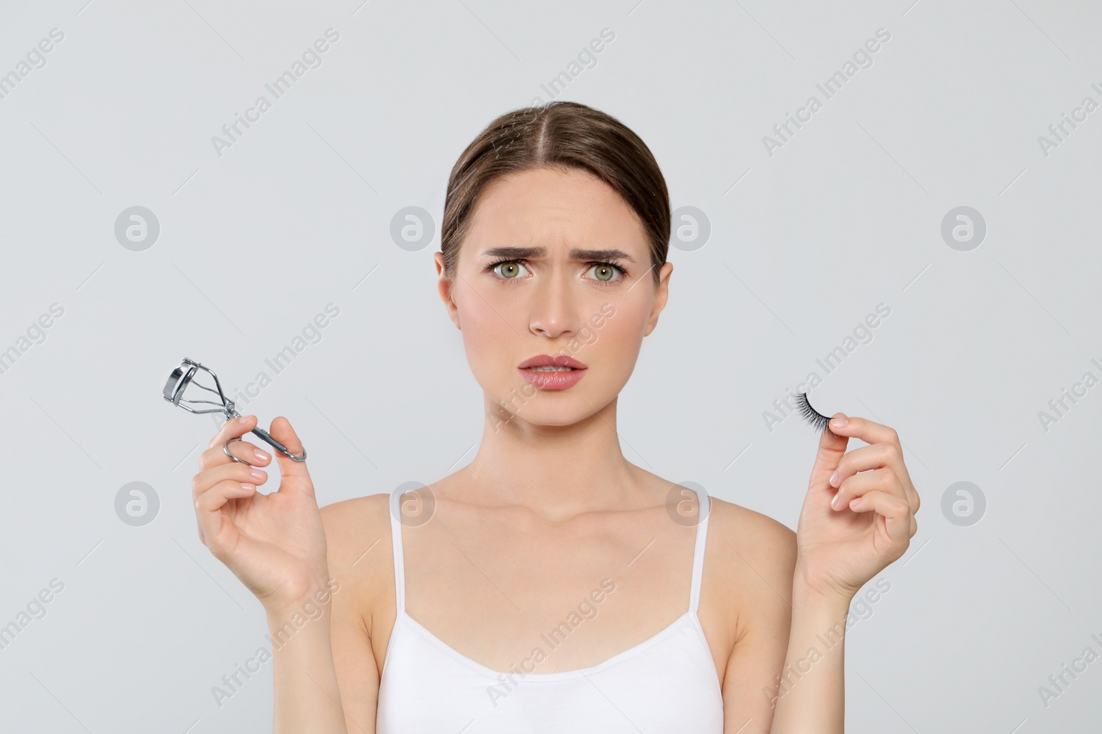 Photo of Emotional woman with curler and false eyelashes on white background