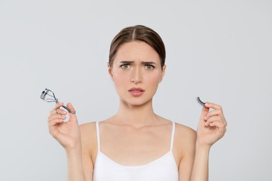 Emotional woman with curler and false eyelashes on white background
