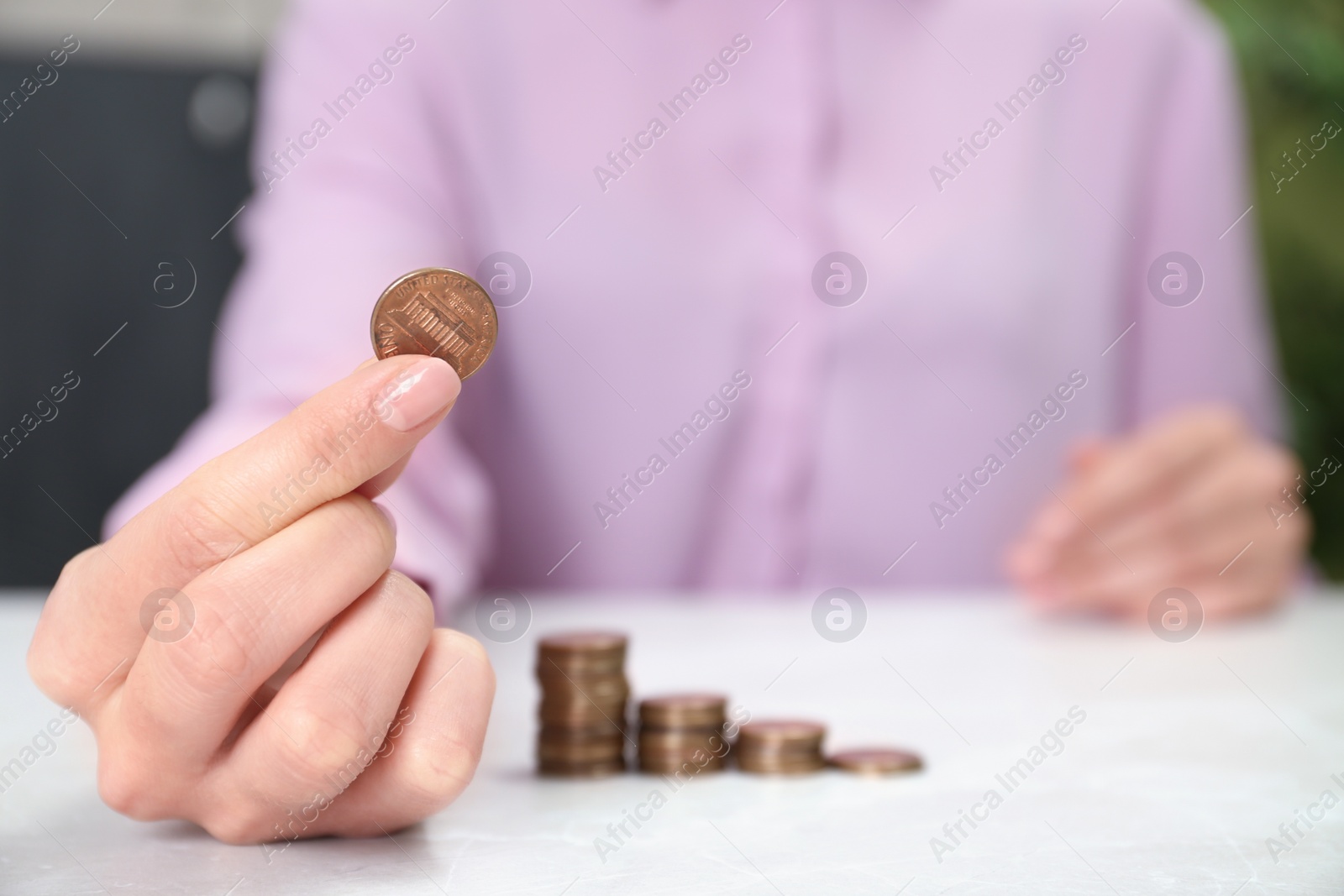 Photo of Woman holding coin at light table indoors, closeup