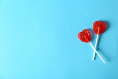 Heart shaped lollipops and space  text  color background, top view. Sweet love