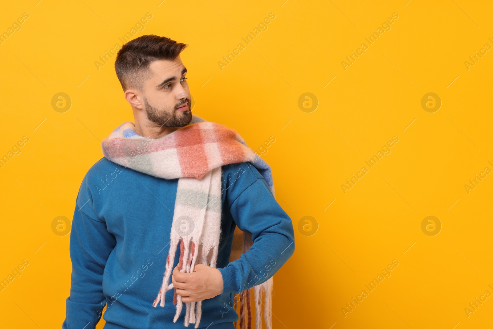 Photo of Handsome man in warm scarf on yellow background. Space for text