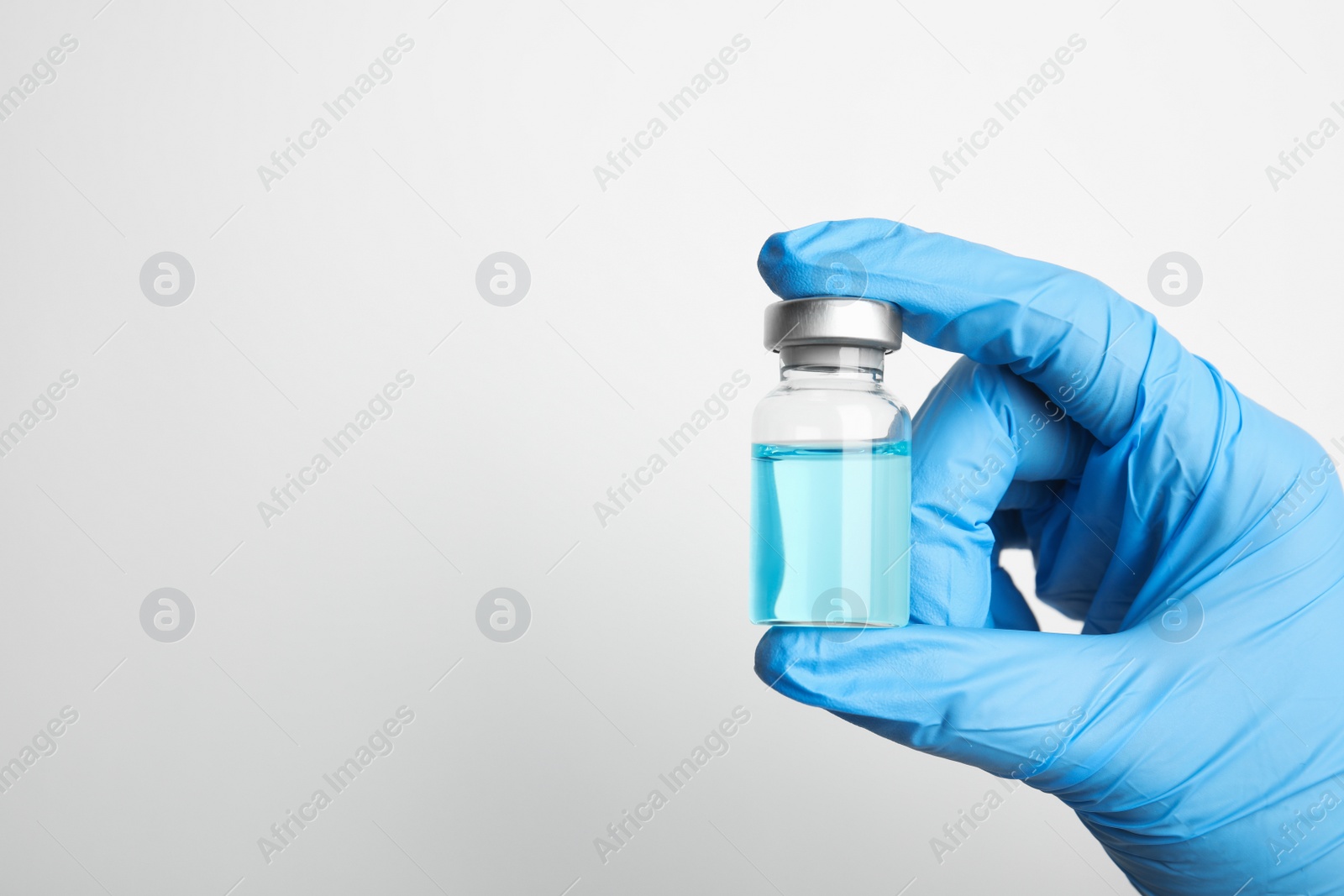 Photo of Doctor holding vial with medication on white background, closeup view and space for text. Vaccination and immunization