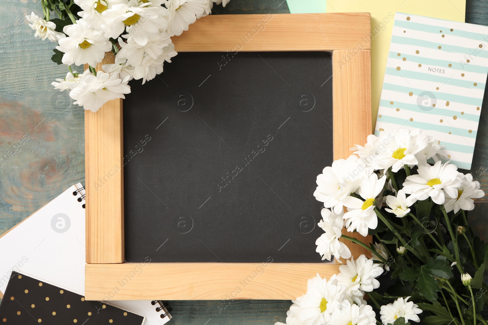 Photo of Blackboard, stationery and flowers on blue wooden table, flat lay with space for text. Teacher's Day