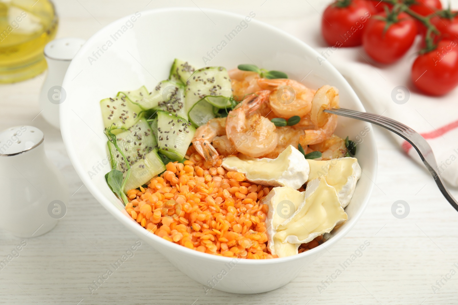 Photo of Delicious lentil bowl with shrimps, soft cheese and cucumber on white wooden table