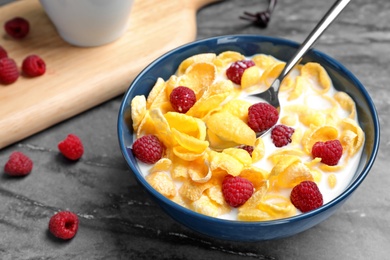 Photo of Bowl with cornflakes and milk on dark table. Whole grain cereal for breakfast