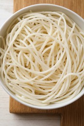 Bowl of tasty cooked rice noodles on white wooden table, top view