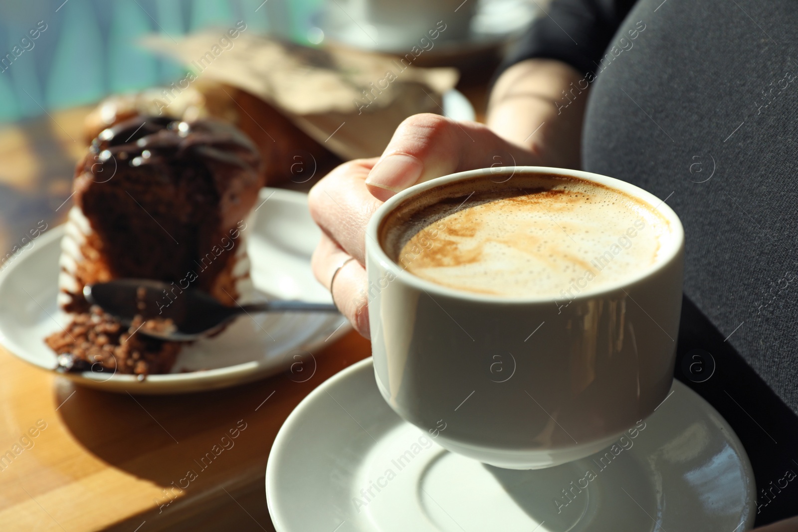 Photo of Woman with cup of fresh aromatic coffee at table in cafe