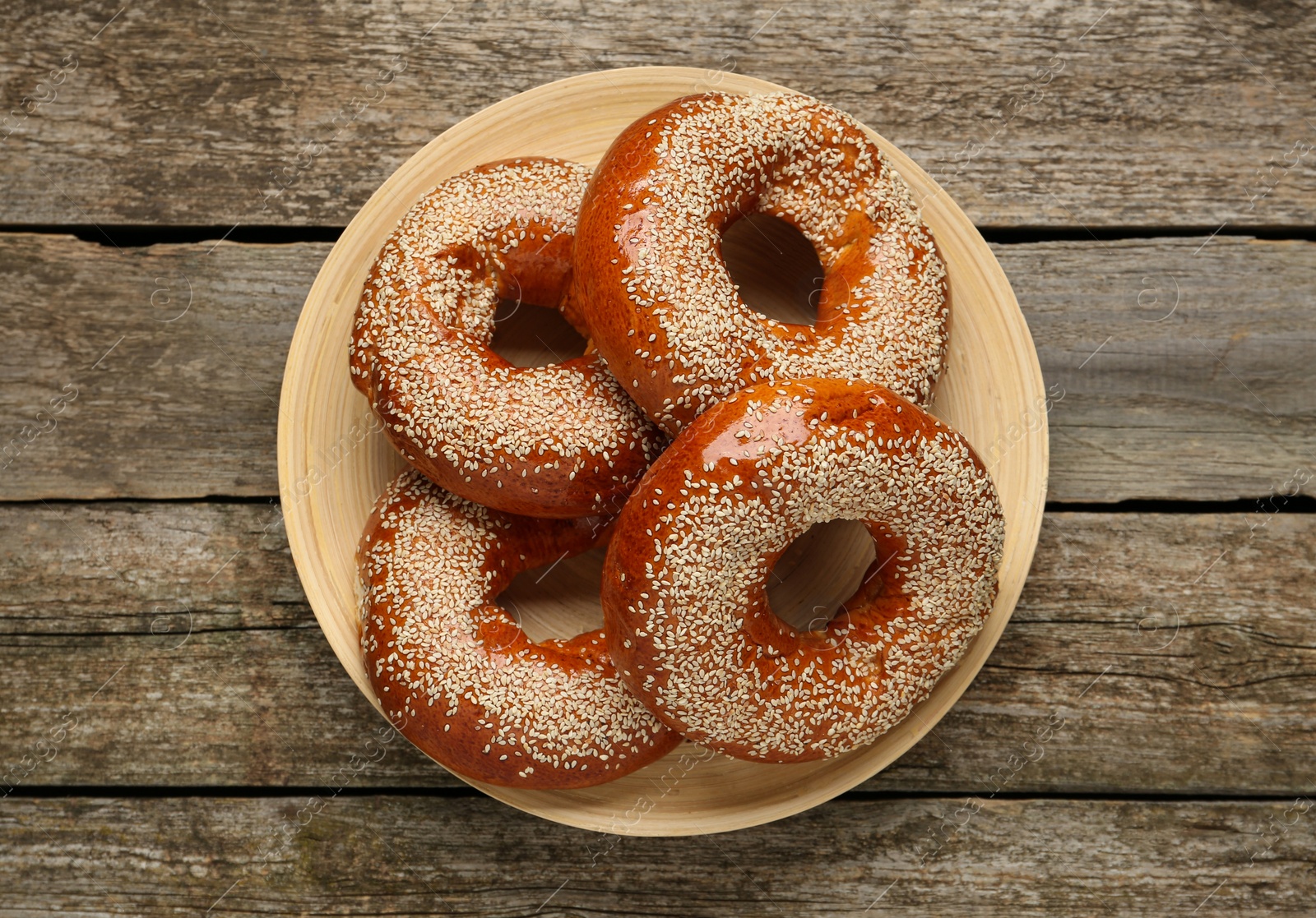 Photo of Delicious fresh bagels with sesame seeds on wooden table, top view