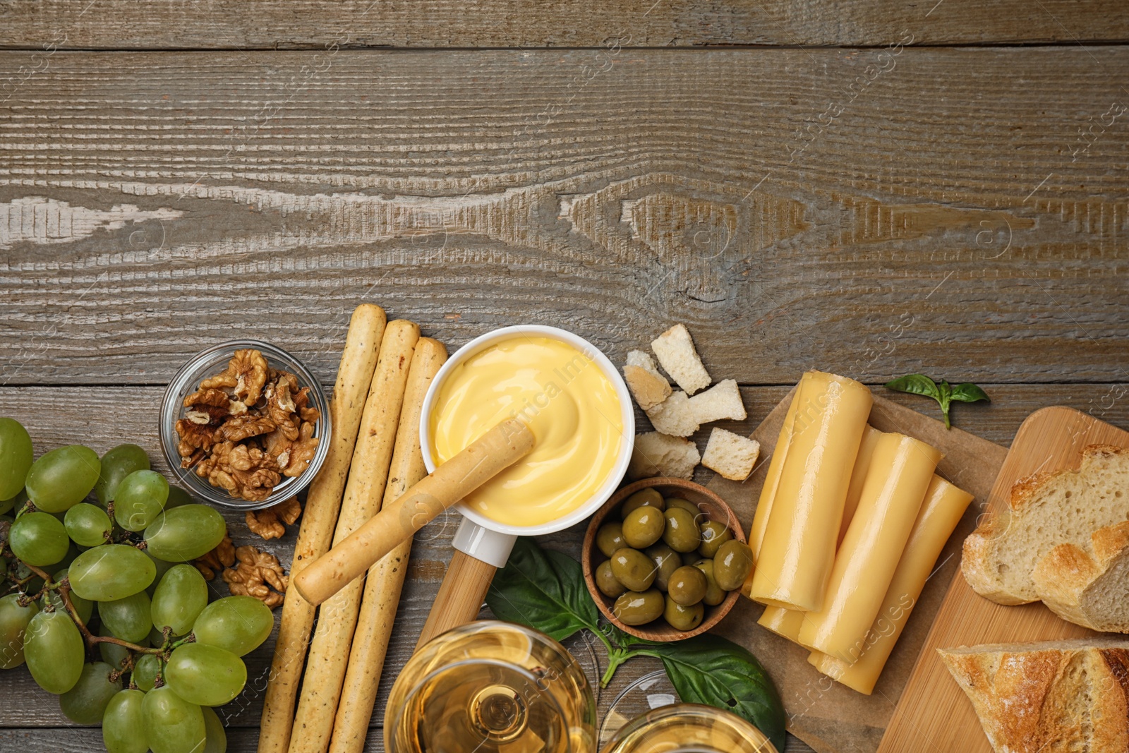 Photo of Flat lay composition with pot of tasty cheese fondue and products on wooden table, space for text