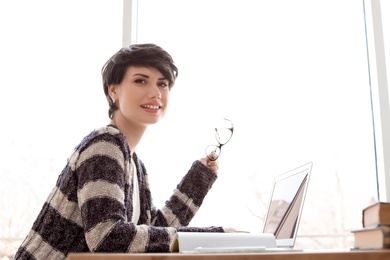 Photo of Young woman working with laptop at desk. Home office