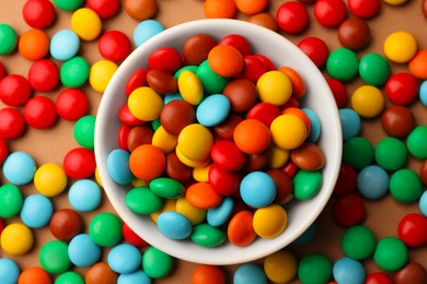 Photo of Tasty colorful candies on light brown background, flat lay