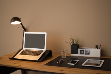 Modern workplace interior with laptop and devices on table. Space for text