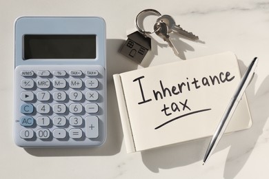 Notepad with phrase Inheritance Tax, calculator and keys with house shaped key chain on white table, flat lay