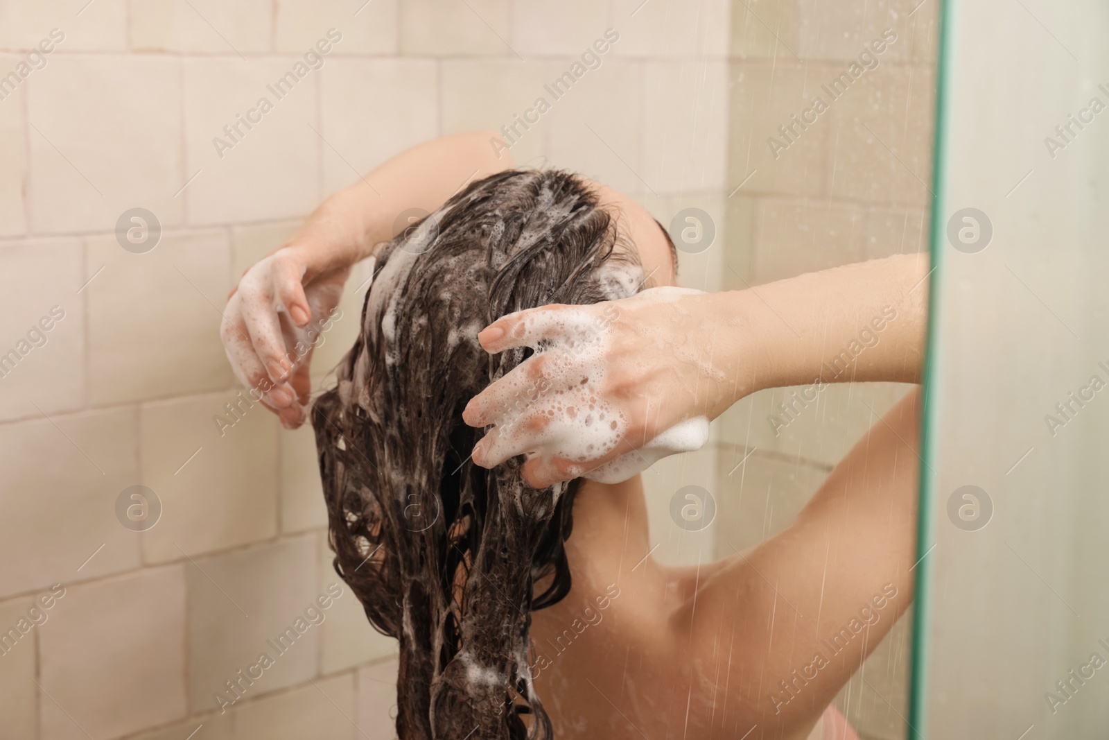 Photo of Young woman washing hair while taking shower at home