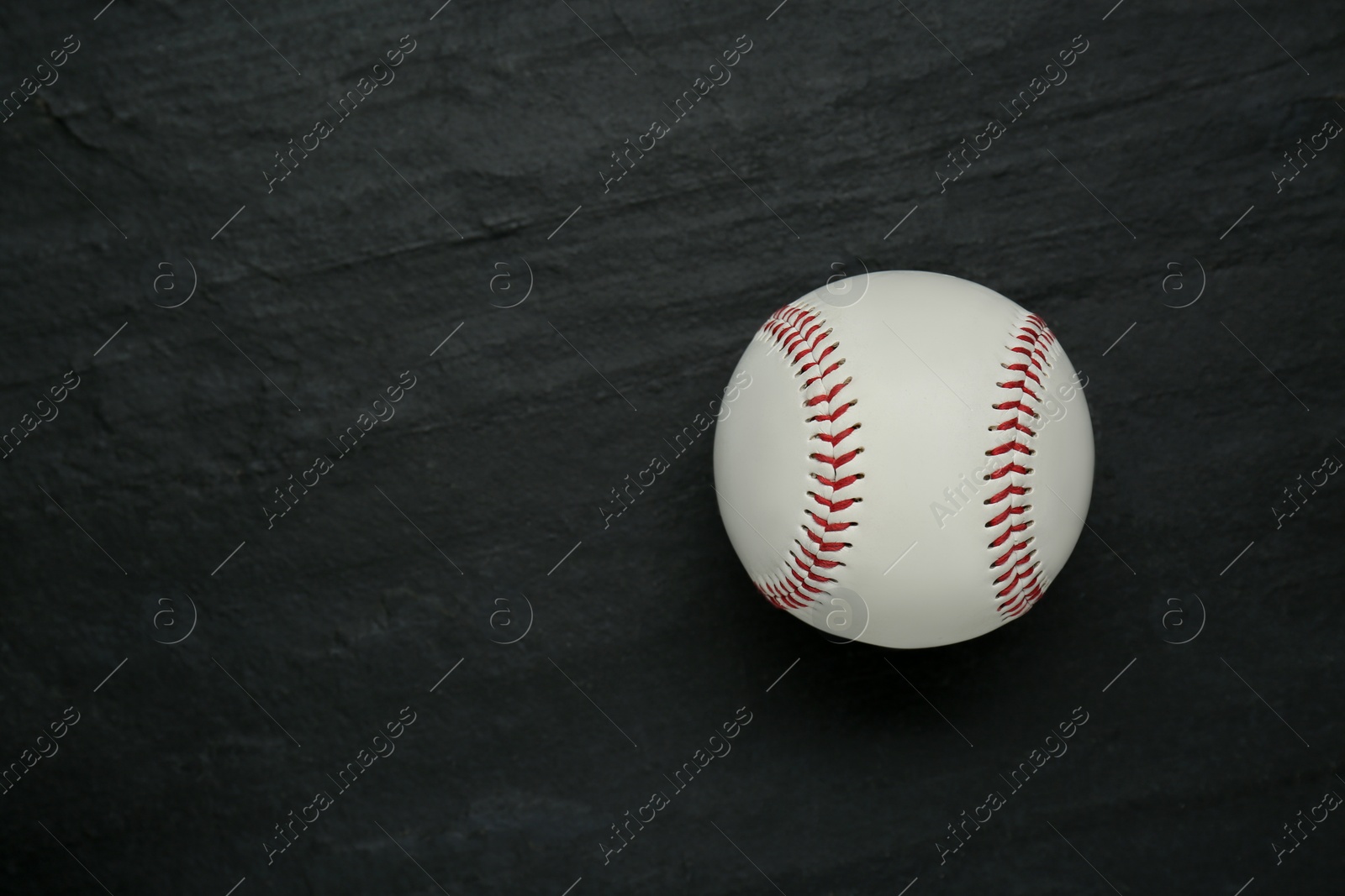 Photo of Baseball ball on black slate background, top view with space for text. Sports game