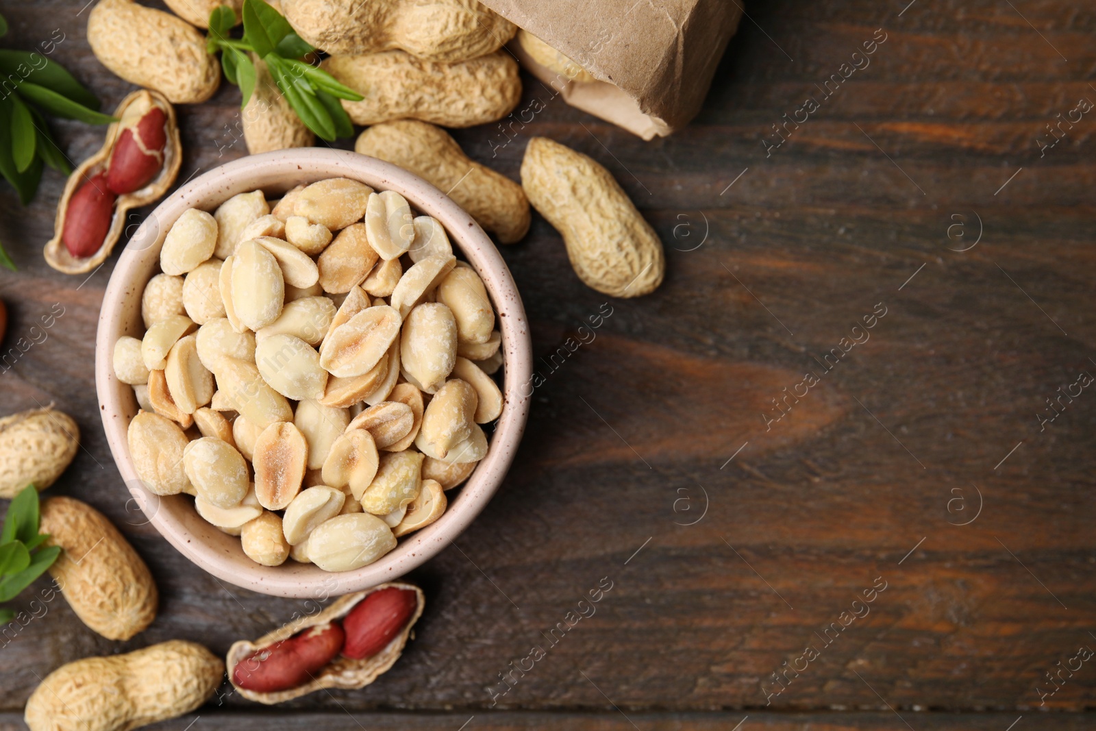 Photo of Fresh peanuts and leaves on wooden table, flat lay. Space for text