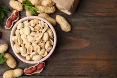 Fresh peanuts and leaves on wooden table, flat lay. Space for text