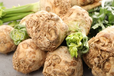 Photo of Many raw celery roots on grey table, closeup
