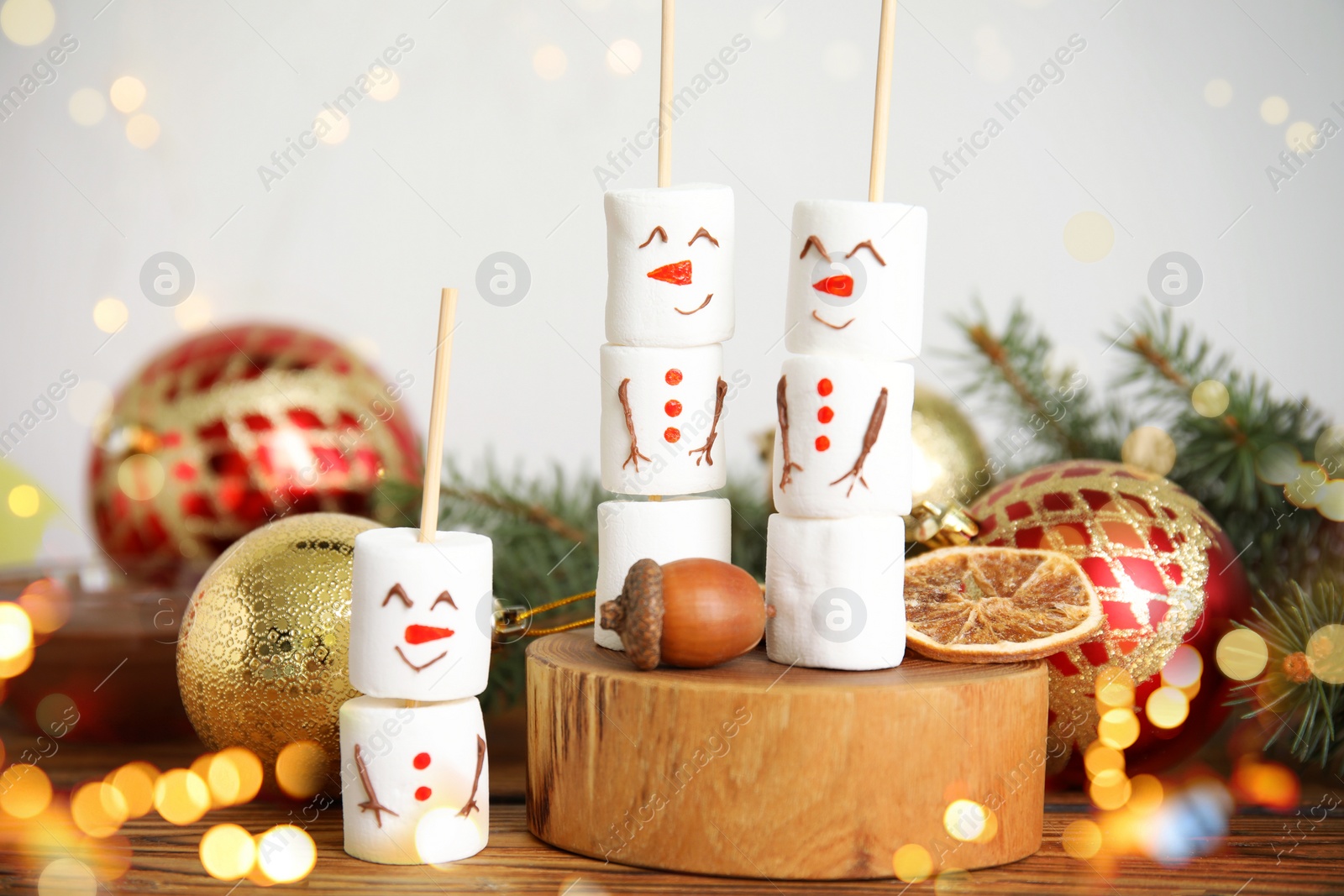 Image of Funny snowmen made of marshmallows and Christmas decor on wooden table. Bokeh effect 