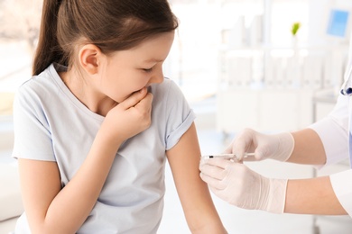 Doctor vaccinating little girl in hospital